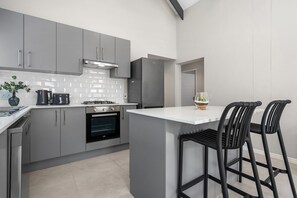 Una cocina moderna con armarios grises, horno empotrado, cafetera y refrigerador.