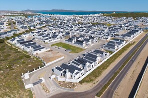 Zona residencial con casas modernas, una carretera y una masa de agua al fondo.