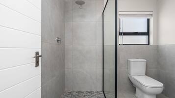 A modern bathroom with a shower, toilet, and a window.