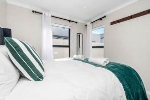 A hotel room with a bed, a window, a door, and a view of the outside. - Langebaan Wildflower (Langebaan)