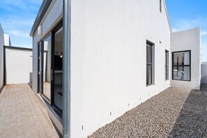 A modern building with a flat roof, large windows, and a gravel pathway. - Langebaan Wildflower (Langebaan)