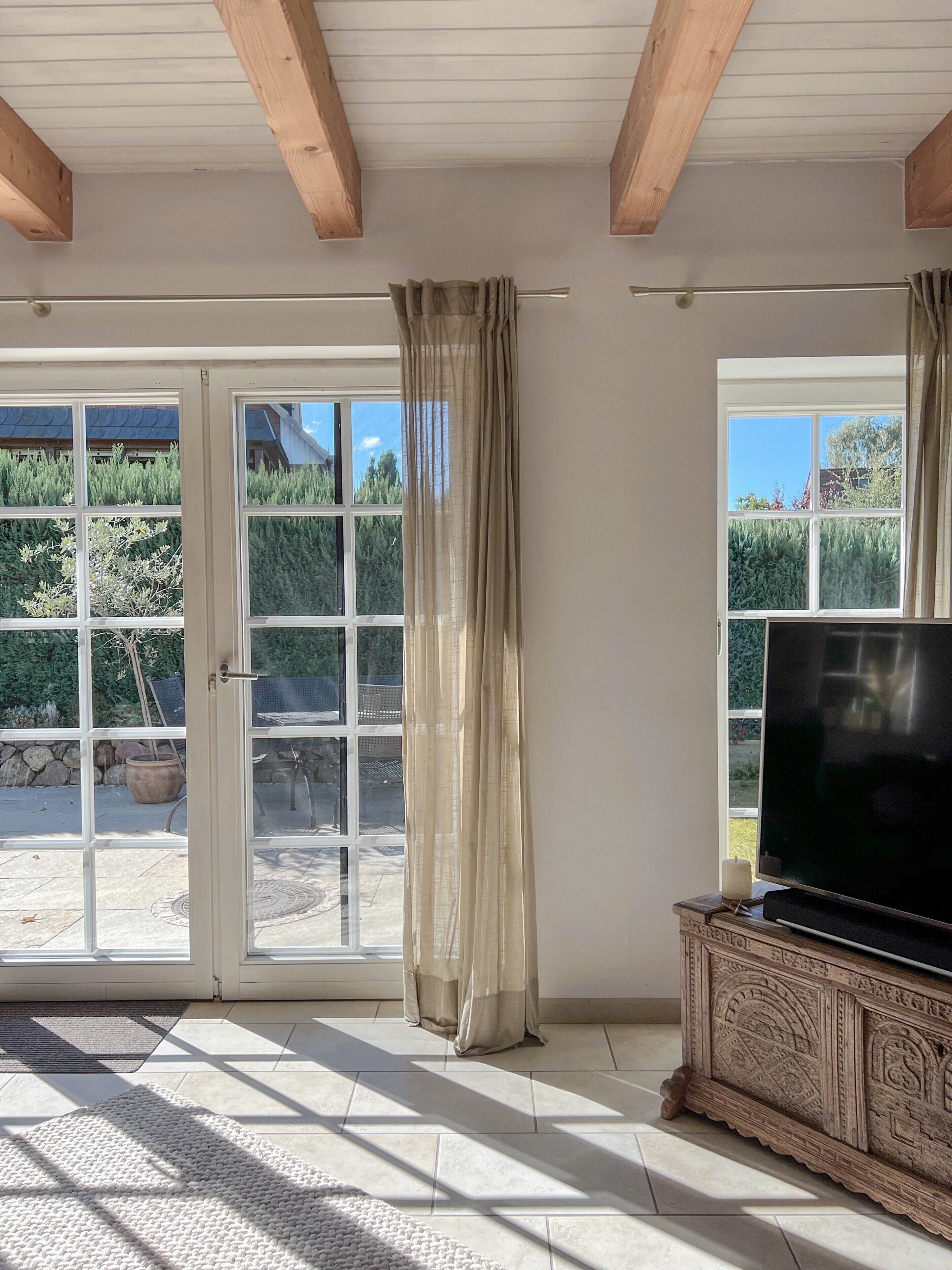 Una stanza con un'ampia porta-finestra in vetro, un televisore su un mobile in legno e un tappeto decorato sul pavimento.