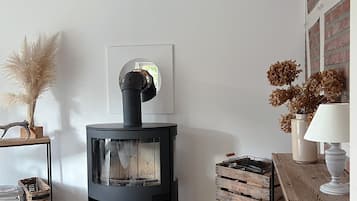 Ett mysigt vardagsrum med en vedeldad kamin, en spegel och rustik inredning.