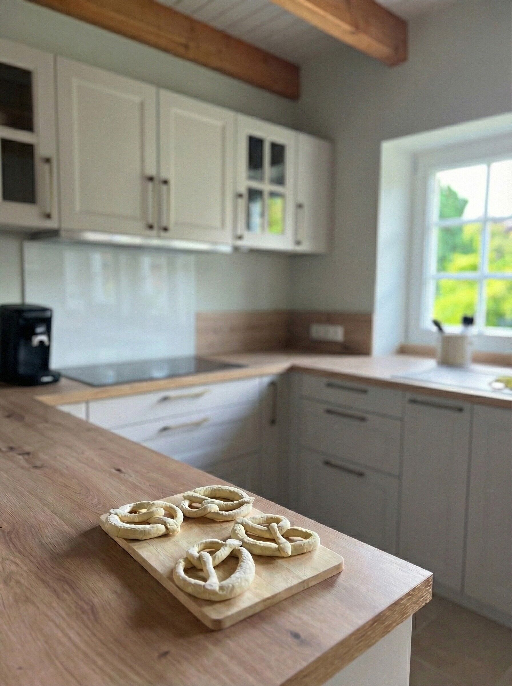 Une cuisine avec des meubles de rangement en bois, un plan de travail en bois et une fenêtre donnant sur un paysage verdoyant.