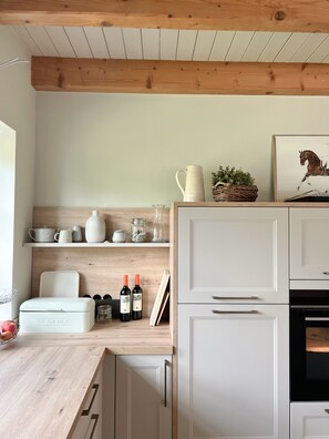 Una cocina con armarios blancos, encimeras de madera y una lámpara colgante.