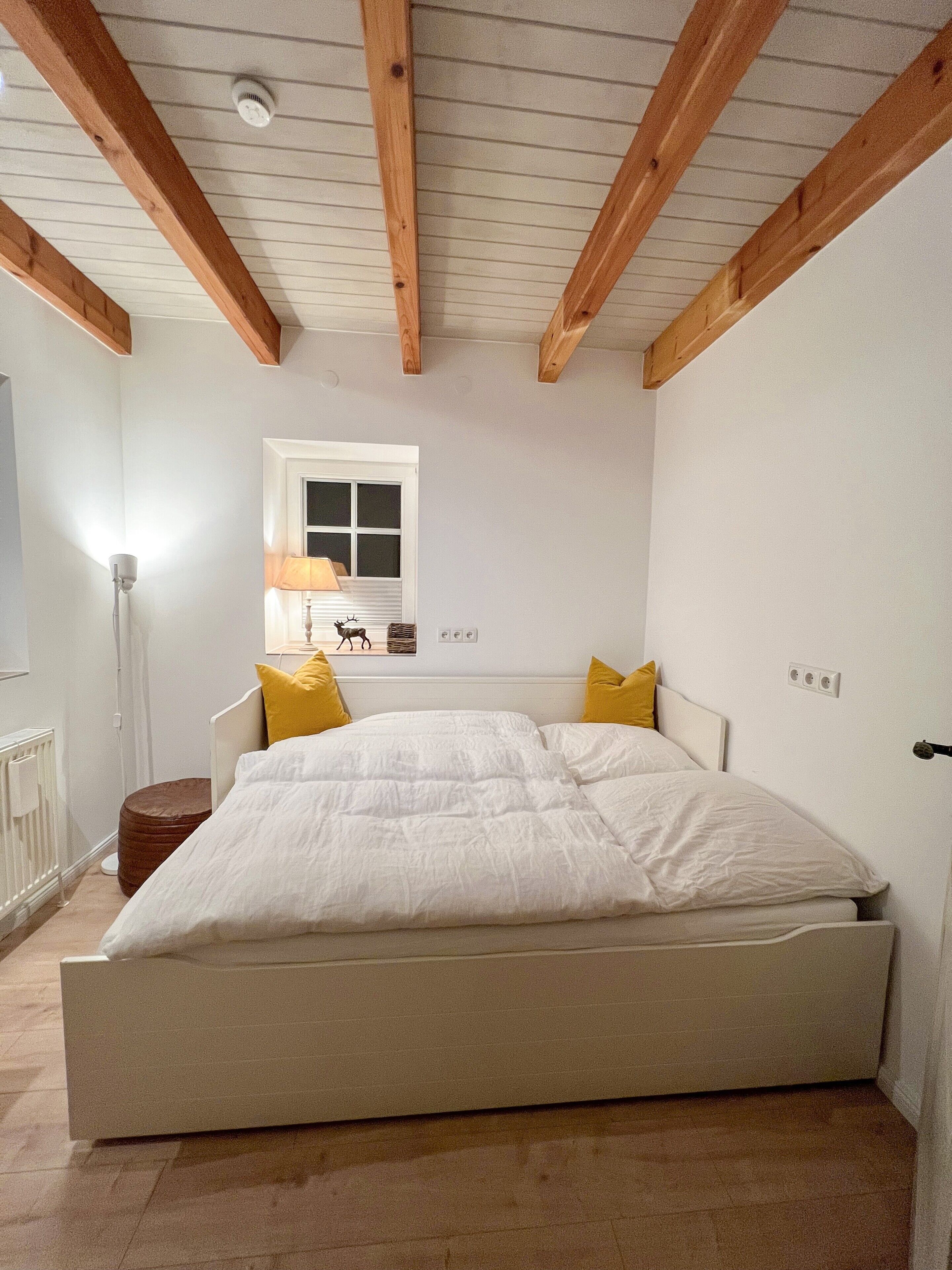 Un dormitorio con cama, ventana, lámpara y radiador.