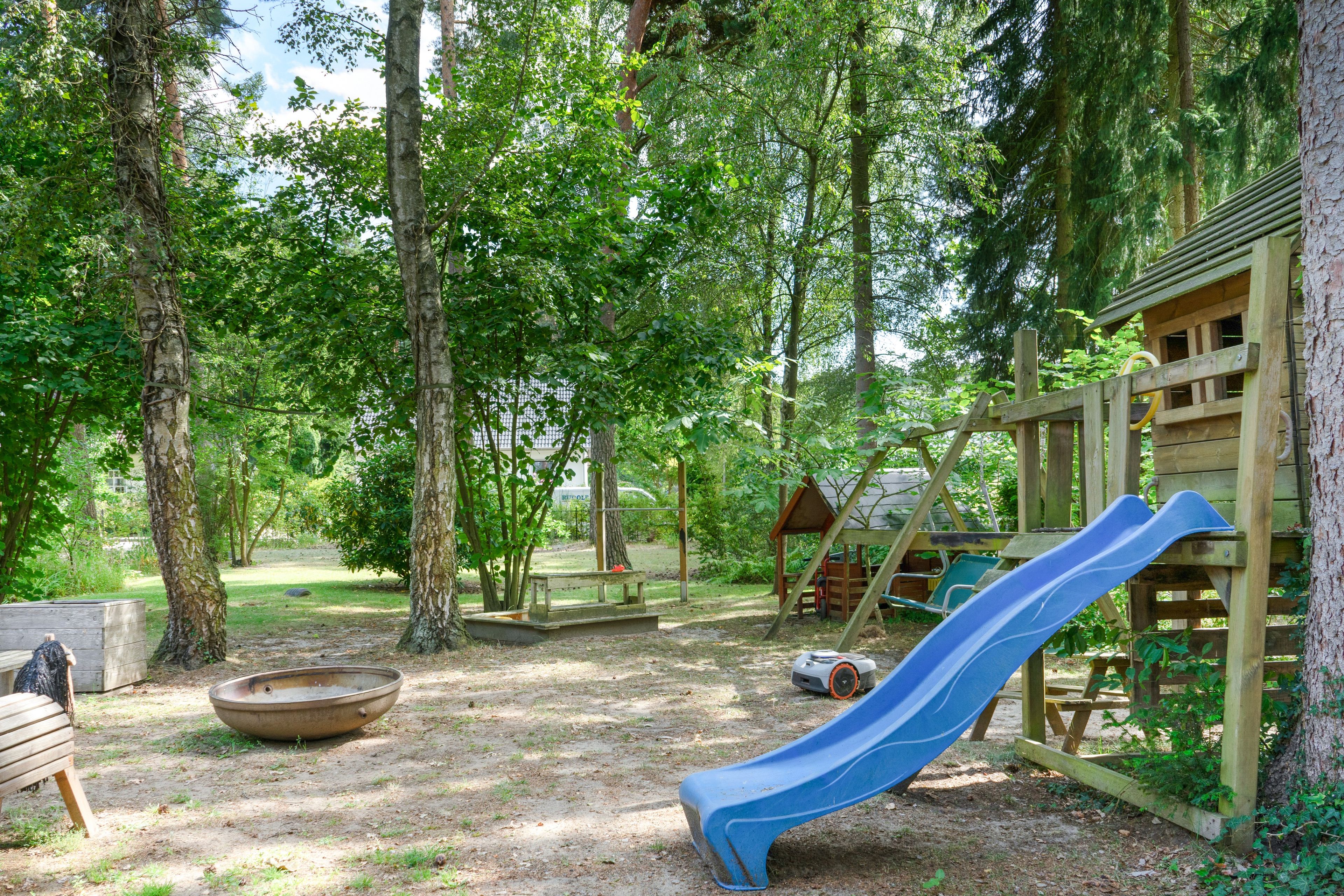A playground with a slide, swings, and a small wooden structure.
