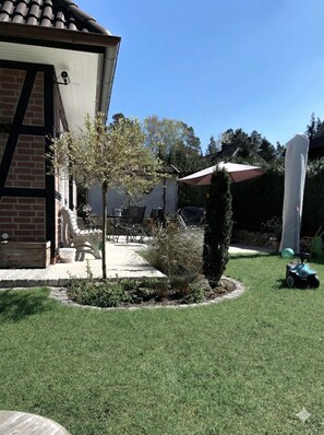 A residential backyard with a patio, a small tree, a lawn, and a shed.