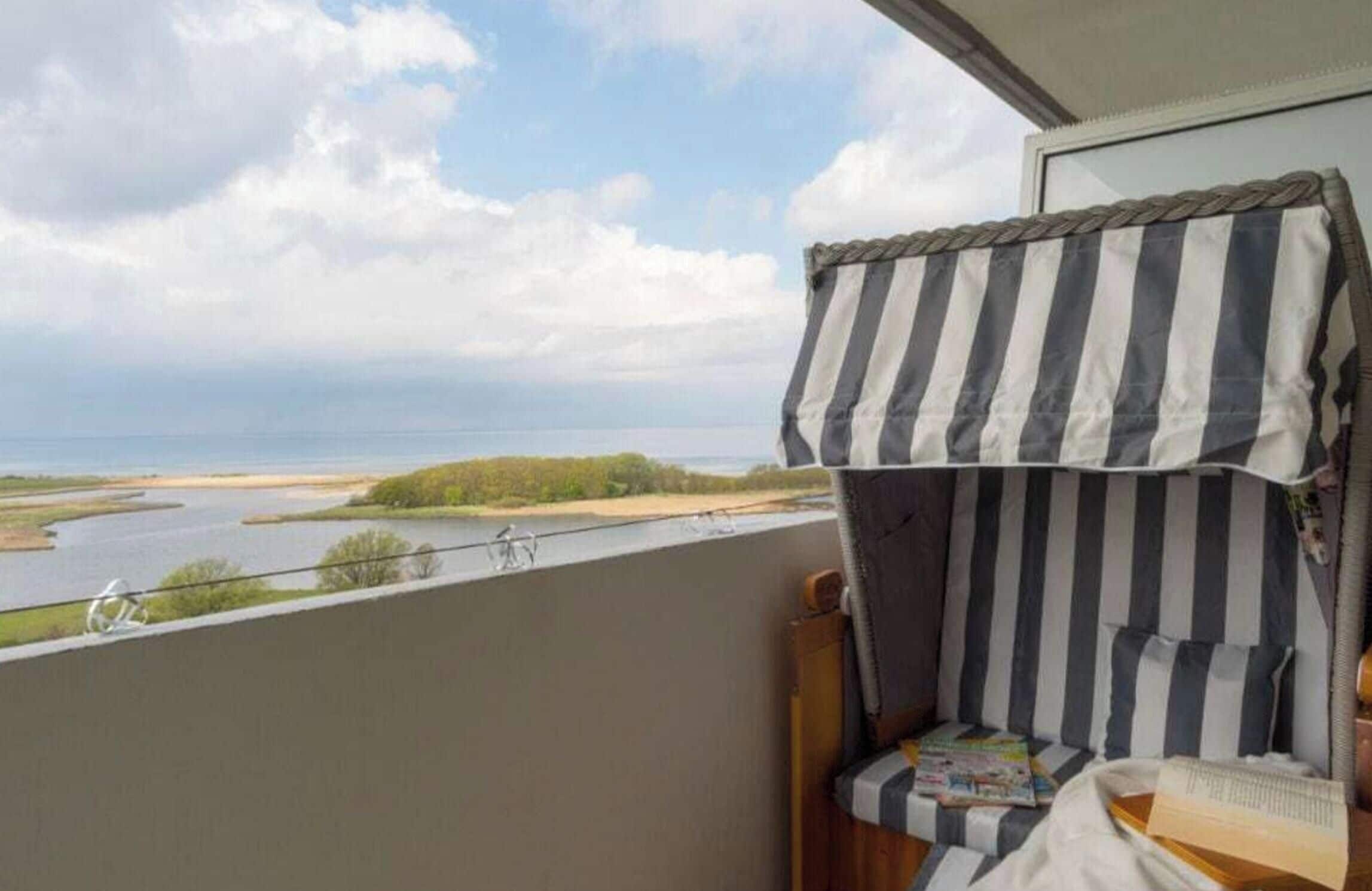 A balcony with a view of a river and a distant shoreline.