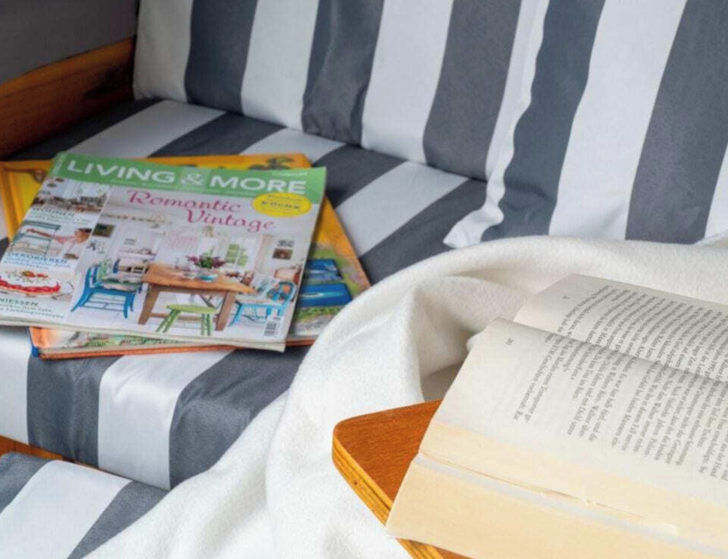 A magazine titled 'Living & More' on a striped sofa.