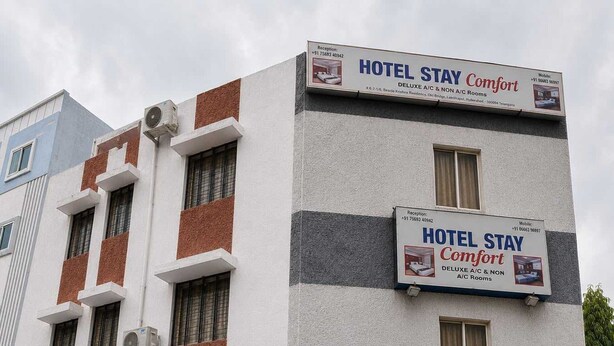 Edifício de hotel com várias placas anunciando 'HOTEL STAY Comfort' e 'Quartos DELUXE com ar condicionado e sem ar condicionado'.