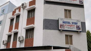 A hotel building with multiple signs advertising 'HOTEL STAY Comfort' and 'DELUXE A/C & NON A/C Rooms'.