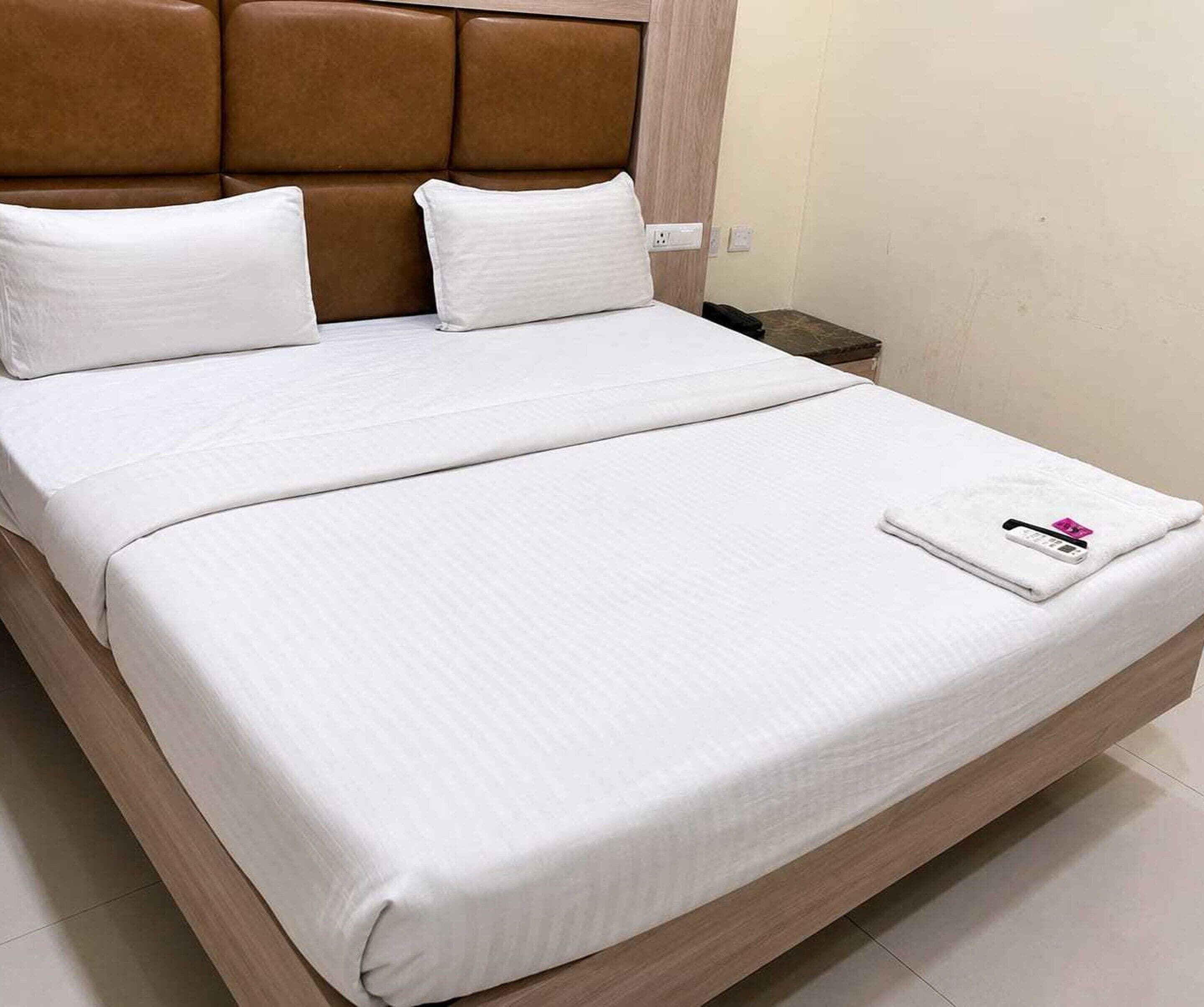 A double bed with white bedding and a brown headboard.