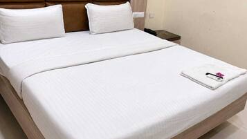 A double bed with white bedding and a brown headboard.