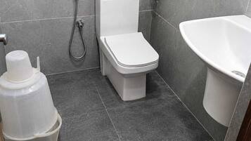 A bathroom with a toilet, a shower, and a sink.