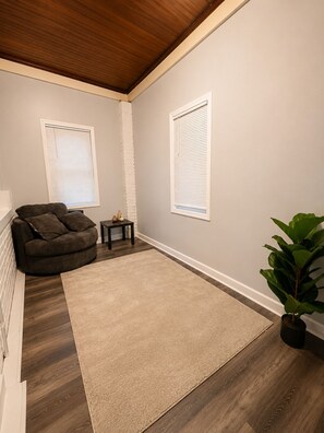 A living room with a dark brown sofa, a small table, a beige rug, and a potted plant.