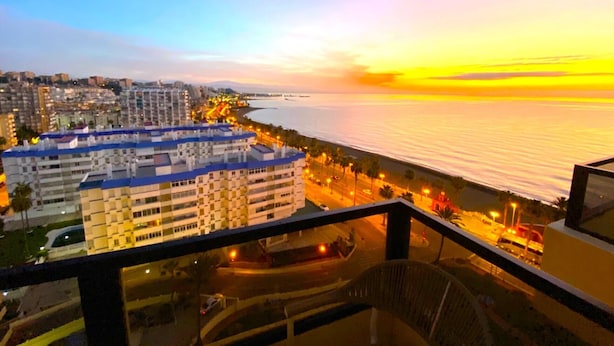 Eine Küstenstadtlandschaft bei Sonnenuntergang mit Hochhäusern und Blick auf das Meer.