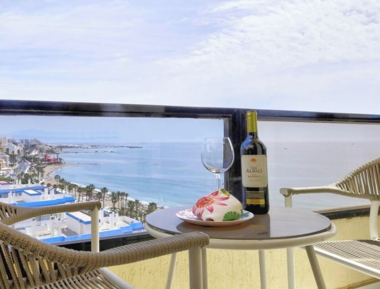 Un balcon avec une table, une bouteille de vin et un verre.