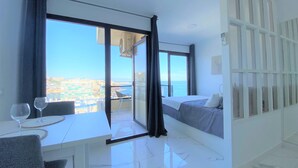 Ein modernes Hotelzimmer mit Balkon, Essbereich und Bett.