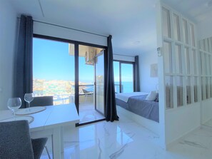 Moderni hotellihuone, jossa on parveke, ruokailutila ja sänky.