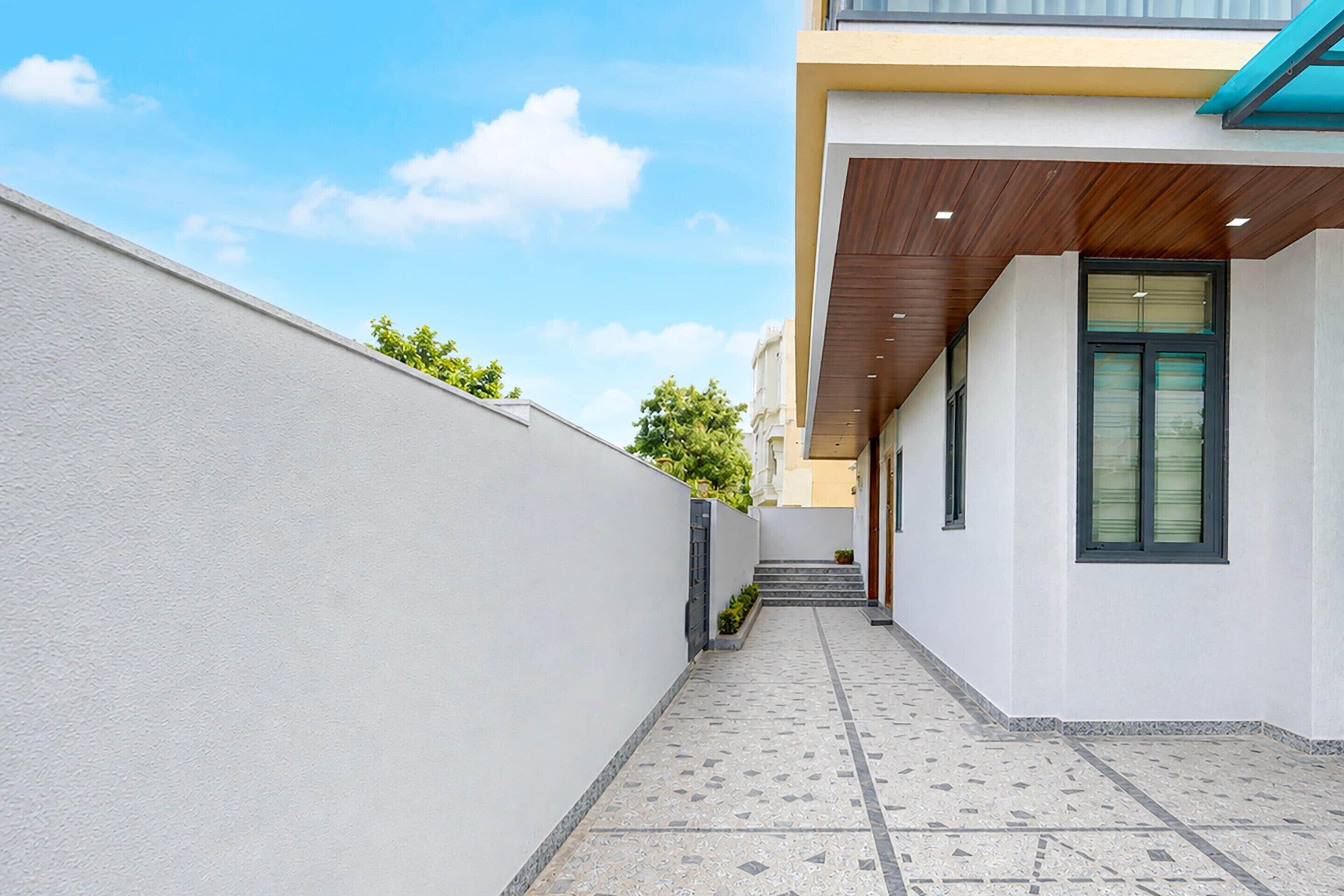 A narrow pathway leading to a building with a wooden ceiling and a door with a window.