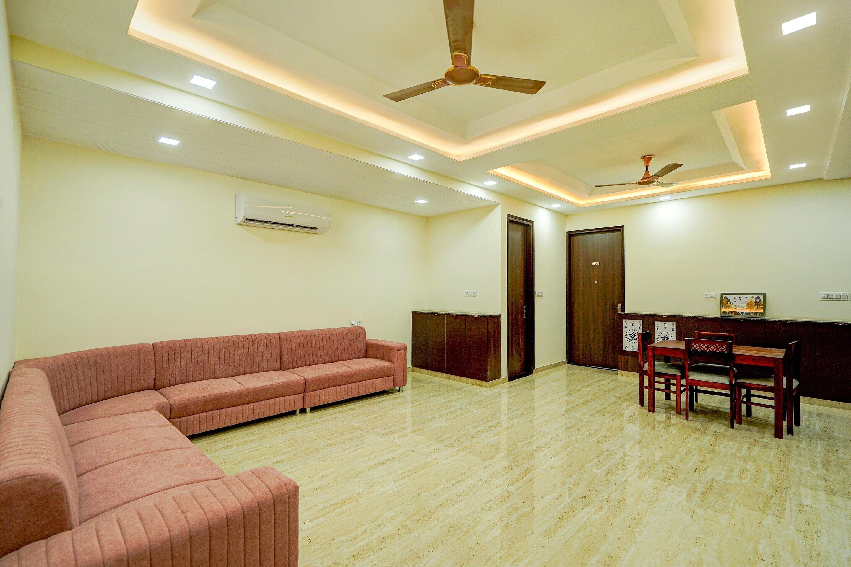 A modern room with a sectional sofa, a dining area with wooden chairs, and ceiling fans.