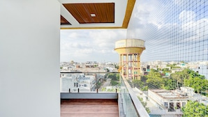 Un balcón con vistas a un paisaje urbano, que incluye un tanque de agua y edificios.