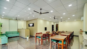 Un salón de conferencias con un sofá verde, mesas y sillas de madera, un ventilador de techo y un letrero que dice 'PALETTE'.