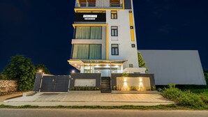 Un edificio residencial de varios pisos con diseño moderno, que destaca por una entrada imponente con un camino de acceso portón y una escalera visible, además de un techo plano.