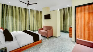 Una habitación de hotel con una cama, una silla, un televisor y un divisor corredizo.