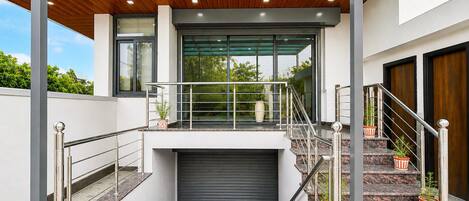 A modern building with a covered outdoor area, a staircase, and a garage door.