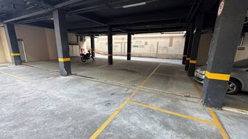 A parking garage with concrete floors, yellow lines, and black pillars with yellow stripes.