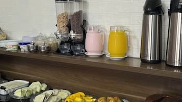 A breakfast buffet area with a sign reading 'Living Café' and various food and drink options.