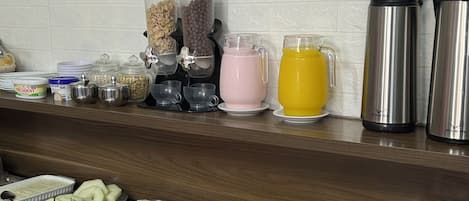 Espaço de buffet de café da manhã com um letreiro que diz 'Living Café' e diversas opções de comida e bebida.