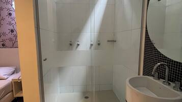 A bathroom with a glass-enclosed shower, a sink, and a mirror.