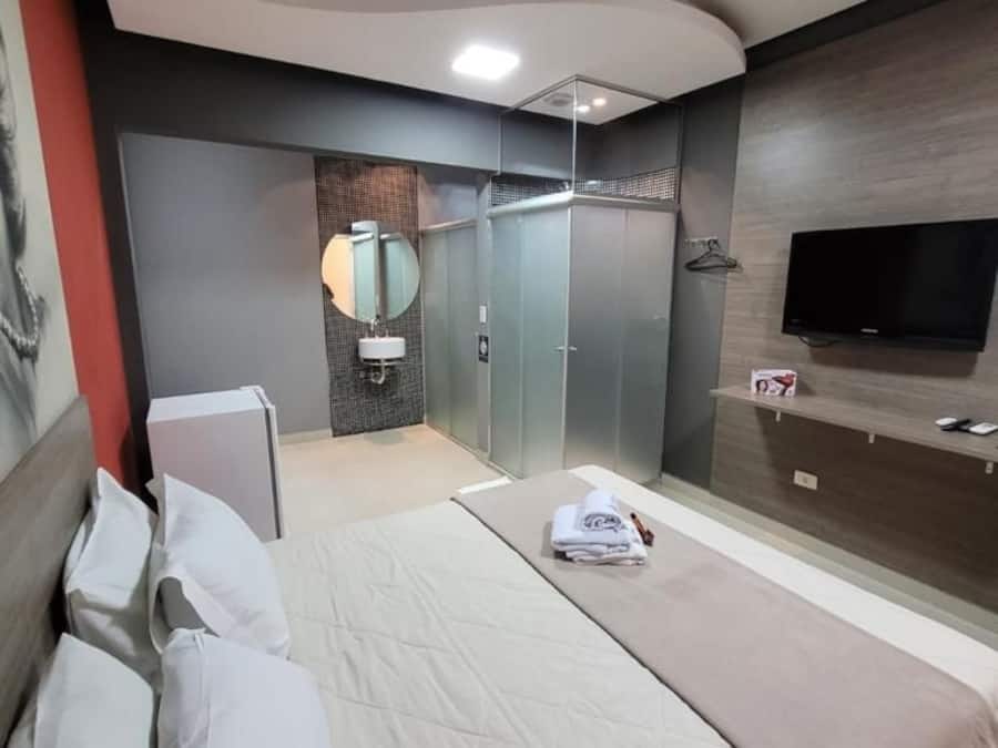 A modern hotel room with a bed, a TV, a mirror, and a wardrobe.