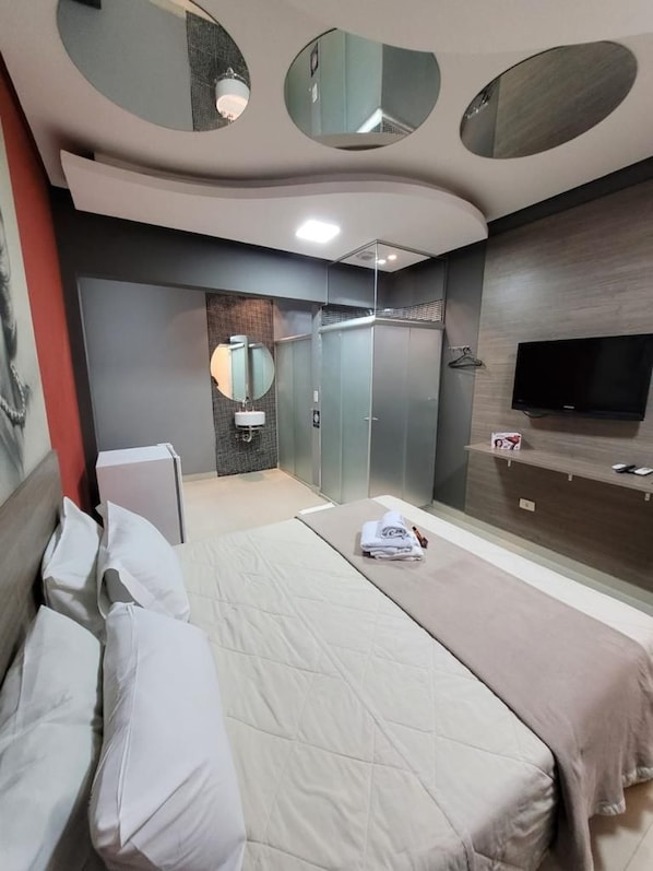 A modern hotel room with a bed, a TV, a mirror, and a wardrobe. - Add Hotéis Center Norte (São Paulo)