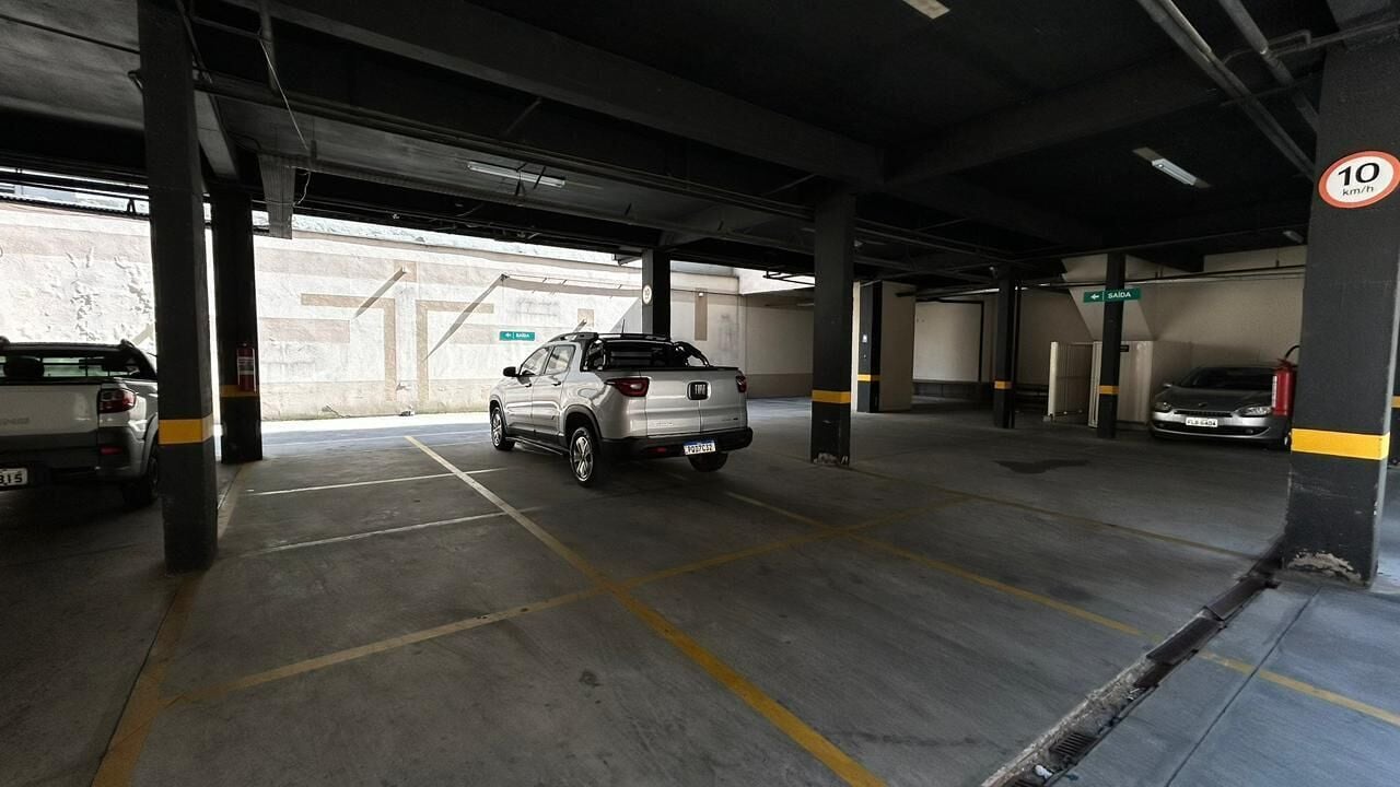 An underground parking garage with concrete pillars, marked parking spaces, and a speed limit sign.