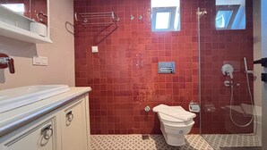 Ein Badezimmer mit rotem Fliesenbelag, einer Toilette, einer Dusche und einem Waschbecken mit Schrank.