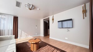Ein modernes Wohnzimmer mit einer Couch, einem runden Couchtisch, einem an der Wand befestigten Flachbildfernseher und Holzboden.