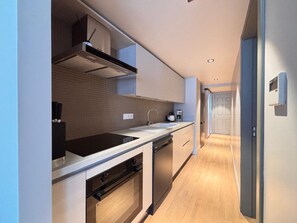 A modern kitchen with a built-in oven, dishwasher, and a stainless steel sink. - Chic 1BR near Karaköy and Galataport (Istanbul)