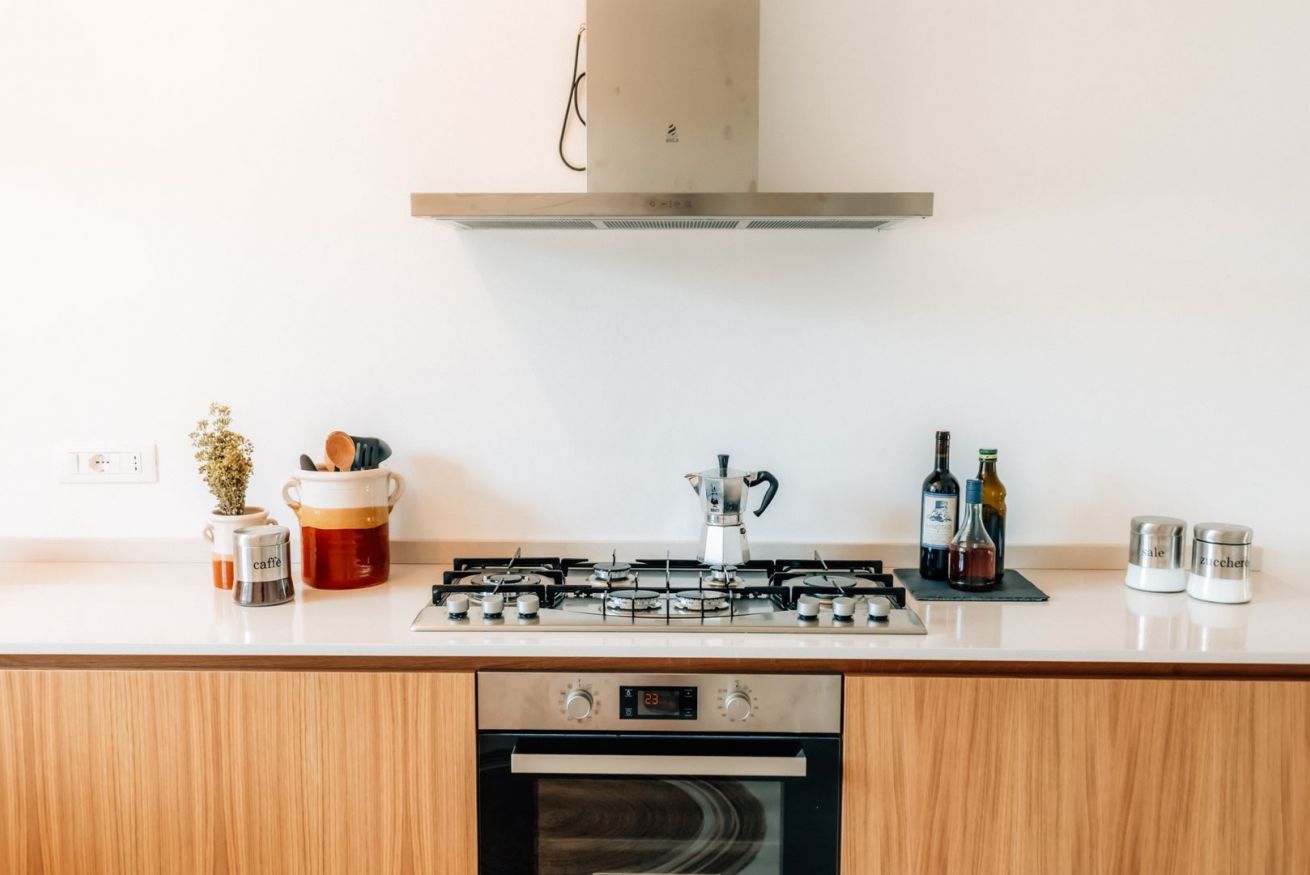 Une cuisine moderne équipée d’une cuisinière à gaz, d’un four et d’une hotte en acier inoxydable.