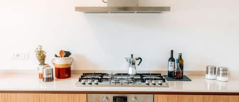 Une cuisine moderne équipée d’une cuisinière à gaz, d’un four et d’une hotte en acier inoxydable.