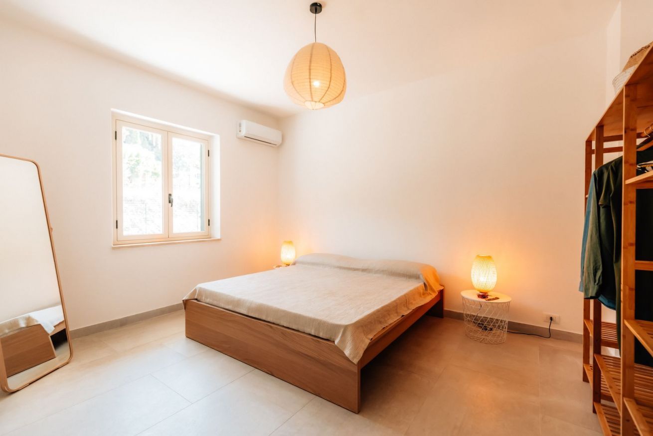 Un dormitorio con cama, lámparas de noche, un armario y una ventana.