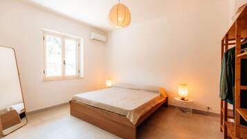 Un dormitorio con cama, lámparas de noche, un armario y una ventana.