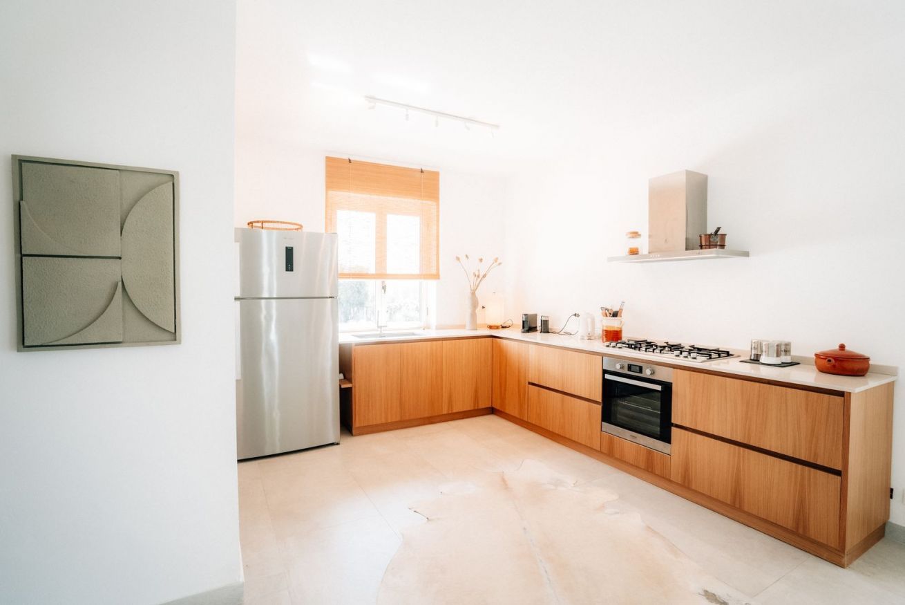 Une cuisine moderne avec des meubles en bois, un réfrigérateur en acier inoxydable et une cuisinière à gaz.