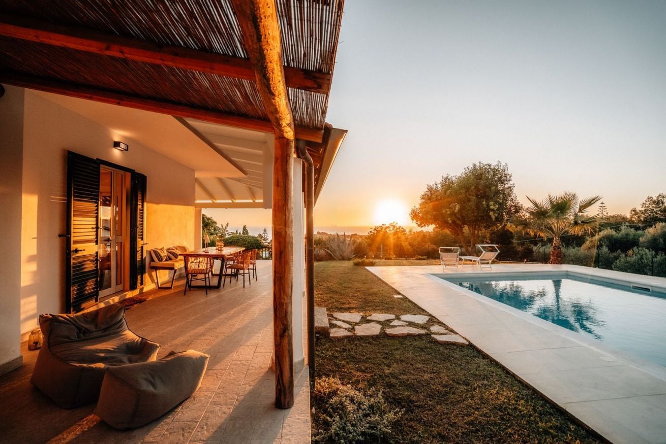 Eine moderne Außenpatio mit Pool, Sitzgelegenheit und Blick auf den Sonnenuntergang.