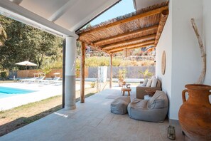 Zona d'estar exterior coberta amb piscina, gandules i un disseny rústic.