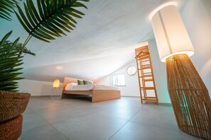 A modern bedroom with a bed, bedside lamp, and a large floor lamp.