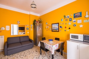 A compact living space with a sofa, dining table, refrigerator, and microwave. - Colli Aminei Vista Golfo (Naples)